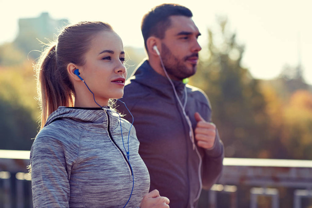 happy couple with earphones running in city - Фото, зображення