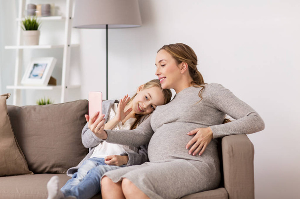 pregnant woman and girl taking smartphone selfie - Foto, imagen