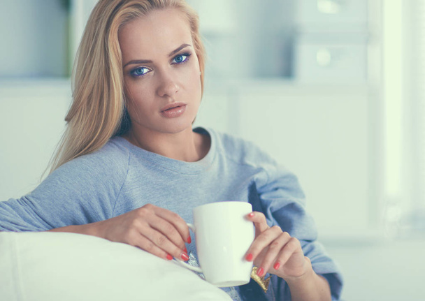 Woman sitting on the couch with cup in her hands - Foto, imagen