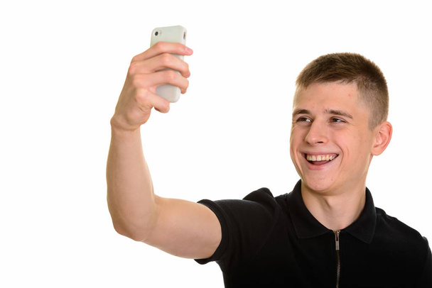 Young happy Caucasian man smiling and taking selfie with mobile  - Photo, Image