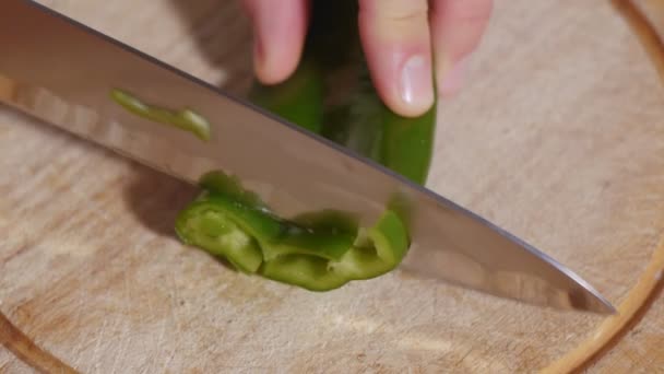 Mans hand starts cutting sweet pepper slices with big serrated knife - Video, Çekim