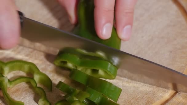 Mans hand cuts sweet pepper slices with big serrated knife - Video, Çekim