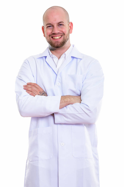 Studio shot of young happy bald muscular man doctor smiling and standing with arms crossed - Фото, изображение