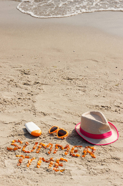 Czas letni napis, Okulary przeciwsłoneczne, krem przeciwsłoneczny i słomkowy kapelusz na piasku plaży, czas letni - Zdjęcie, obraz