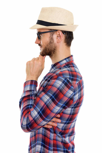 Profile view of young man thinking while wearing eyeglasses and hat - 写真・画像