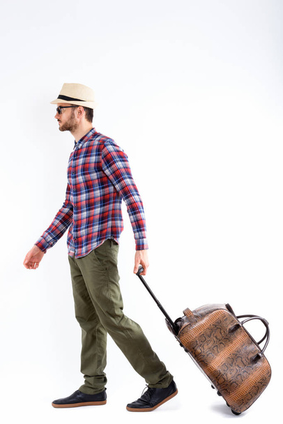 Full body shot of profile view of young man carrying bag ready for vacation - Фото, изображение