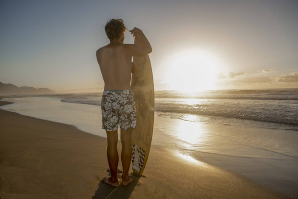 Young surfer on beach with voard at dawn - Foto, Imagen
