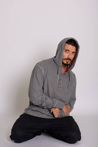 Studio shot of handsome man looking scared while kneeling - Photo, Image