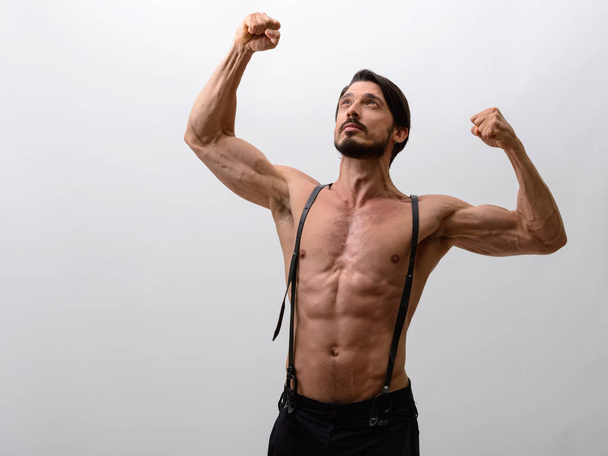 Studio shot of handsome man flexing both arms while looking up shirtless - Foto, imagen