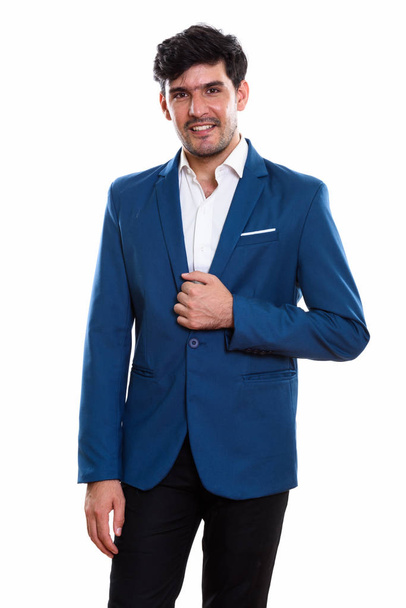 Studio shot of young happy Persian businessman smiling while holding jacket - Foto, imagen