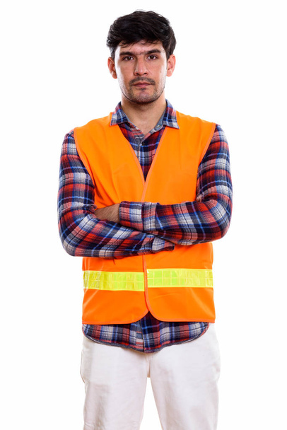 Studio shot of young Persian man construction worker standing with arms crossed - Valokuva, kuva