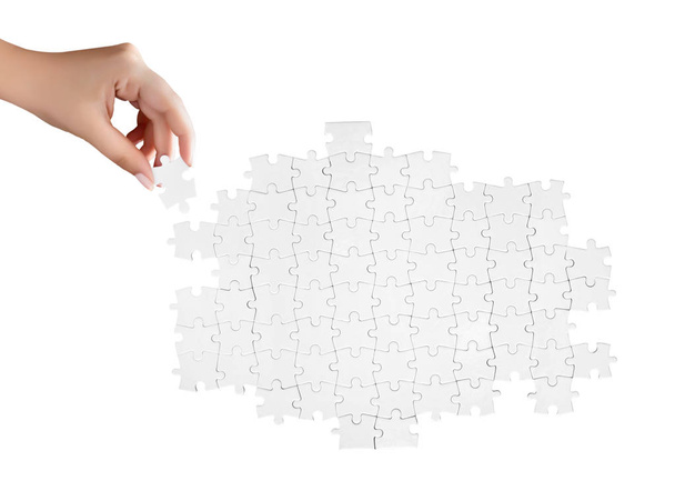 ruka držící kousek bílé nedokončeného puzzle - Fotografie, Obrázek