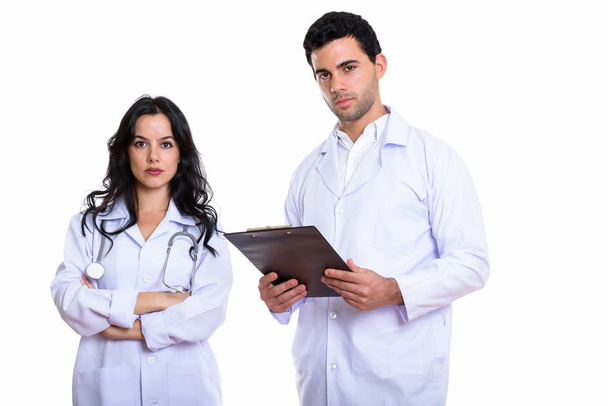 Studio colpo di giovane uomo medico tenendo appunti e donna medico con le braccia incrociate - Foto, immagini