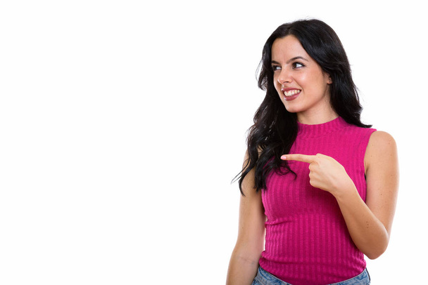 Studio shot of young happy Spanish woman smiling while pointing and looking at side - Photo, Image