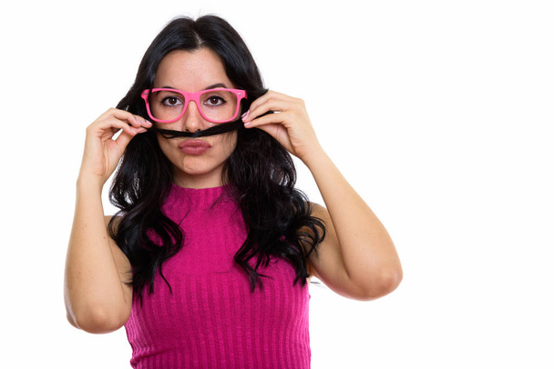 Studio shot of young beautiful Spanish woman using her hair as mustache while wearing eyeglasses - Photo, image