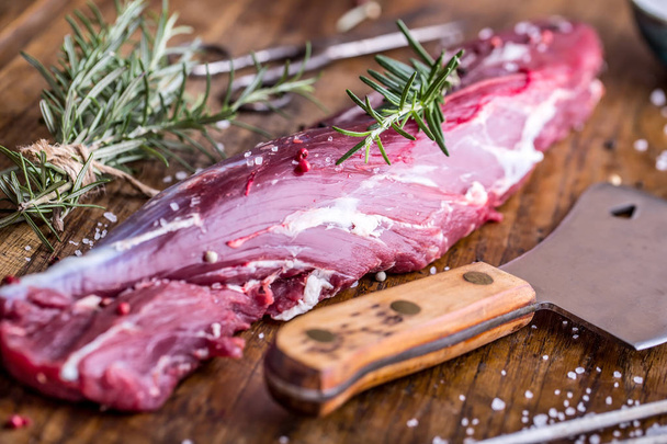 Raw beef meat. Raw beef tenderloin steak on a cutting board with rosemary pepper salt in other positions. - Fotoğraf, Görsel