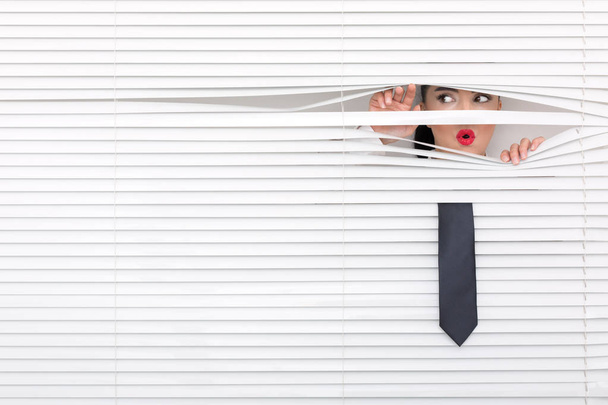 Portret van een vrouw op zoek via de blinds - Foto, afbeelding