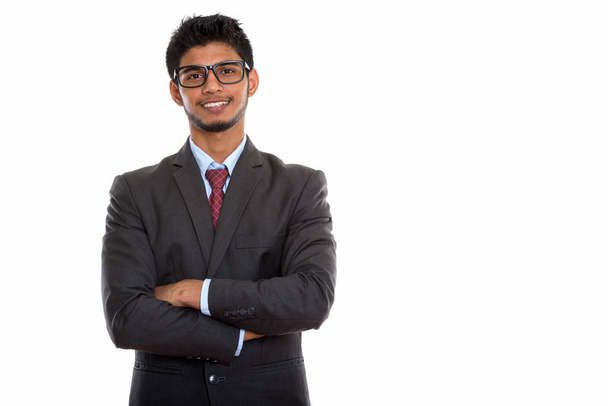 若い幸せなインドのビジネスマンの笑顔のスタジオショット腕で眼鏡をかけながら交差 - 写真・画像