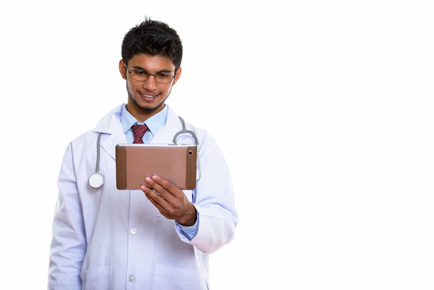 Studio laukaus nuori onnellinen intialainen mies lääkäri hymyilee samalla tilalla digitaalinen tabletti - Valokuva, kuva