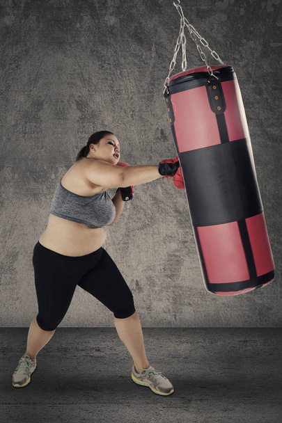 Blonde woman hitting a boxing sack - Fotografie, Obrázek