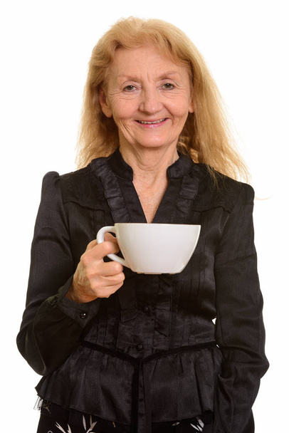 Studio shot of happy senior businesswoman smiling while holding coffee cup - Fotoğraf, Görsel