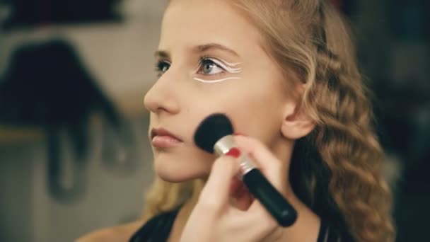 Make-up artist makes young actress girl beautiful makeup for face before dancing perfomance indoors - Felvétel, videó