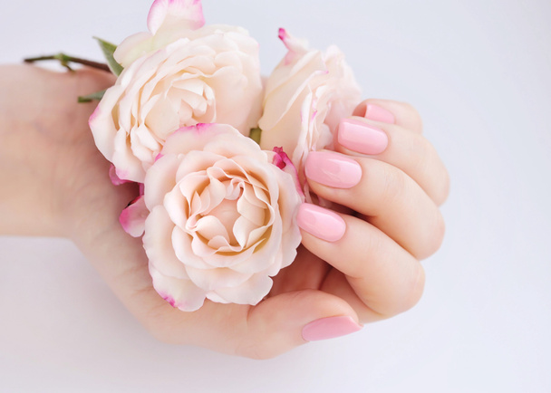 Kezében egy nő, rózsaszín manikűr a köröm és a rózsák - Fotó, kép