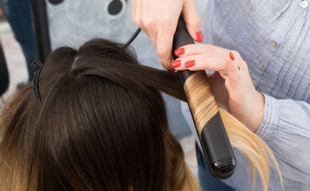 Professional hairdresser curling ombre hair with iron in beauty  - Foto, imagen