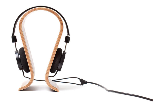 Black Pair of Headphones on a wooden stand. Isolated - Photo, Image