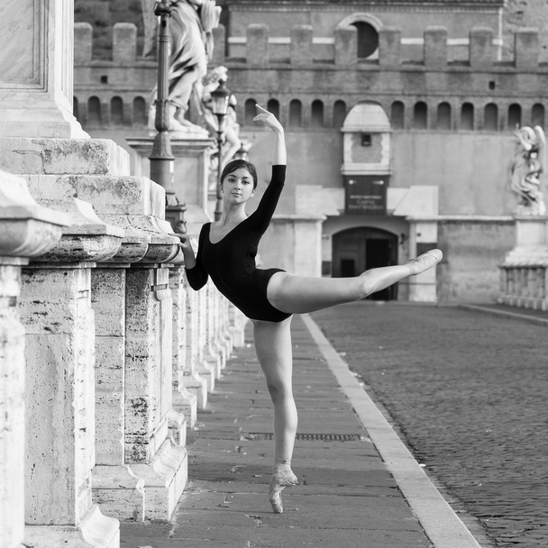 Young beautiful ballerina dancing out in the street in Castel Santangelo bridge in Rome, Italy. Black and white image. Ballerina Project. - Foto, Imagen