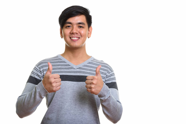 Studio shot van gelukkig Aziatische man glimlachend en duimen opgevend - Foto, afbeelding