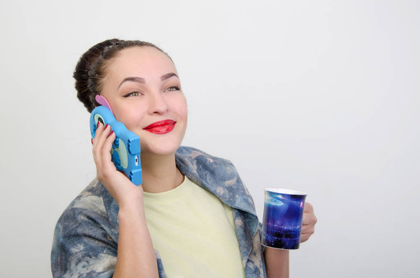 lány egy kék telefon és kupa - Fotó, kép