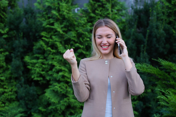 Attractive blond lady talking on phone and holds it in hand, smi - Фото, изображение