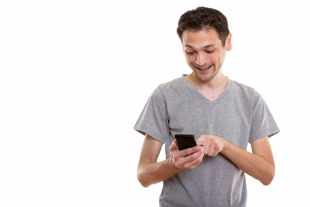 Студійний знімок щасливого молодого чоловіка, який посміхається під час використання мобільного телефону
 - Фото, зображення