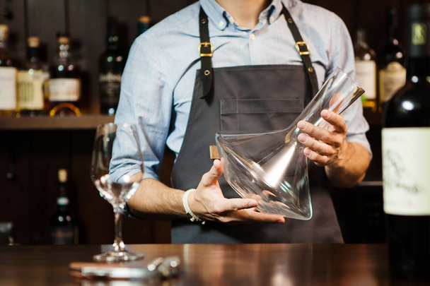 Wineglass at barcounter at background of sommelier with emty decanter - 写真・画像