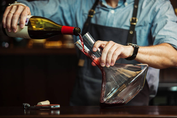 Sommelier pouring red wine into carafe to make perfect color - 写真・画像