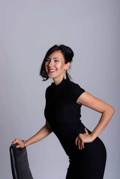 Thoughtful happy businesswoman smiling while kneeling on chair - 写真・画像