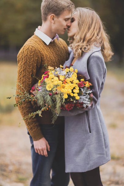 Çiçekler buket üzerinde odaklanın. Güzel genç çift sarılmak portresi - Fotoğraf, Görsel
