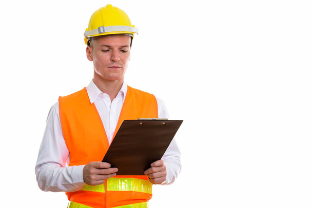 Studio shot of young handsome man construction worker reading on - Photo, Image