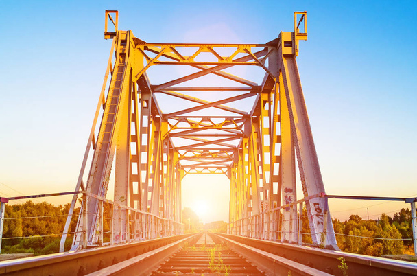 Puente ferroviario en verano puesta de sol y traviesas de hierba
 - Foto, Imagen