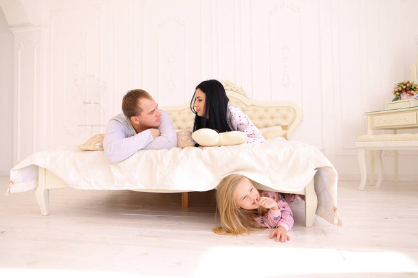 Fille cachée sous le lit, maman et papa parlaient à la maison
 - Photo, image