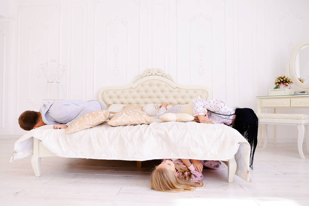 Hija escondida debajo de la cama, mamá y papá buscando un niño en casa
 - Foto, Imagen