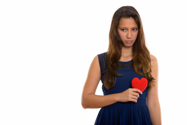 Studio shot of young beautiful woman holding red heart while loo - Photo, Image