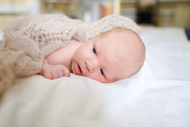 Bebé recién nacido cubierto manta de punto y acostado en la cama en el sueño
 - Foto, Imagen