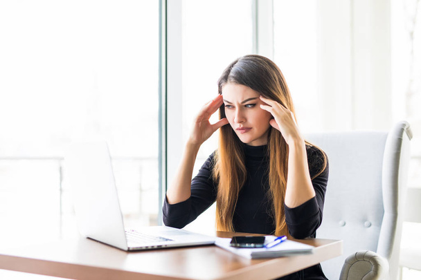 Young attractive woman at modern office desk, working on laptop, massaging temples to forget about constant headaches, noisy loud office giving a migraine, relieving stress, chronic pain, help soothe - Photo, Image
