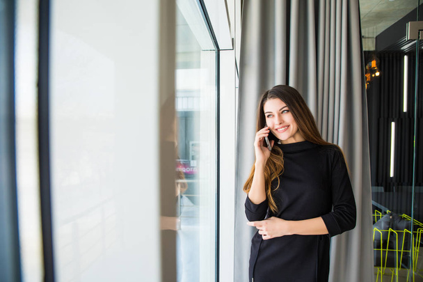 Smiling woman talking on phone in office - Foto, imagen