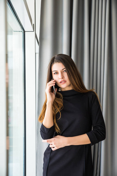 Smiling woman talking on phone in office - Foto, immagini
