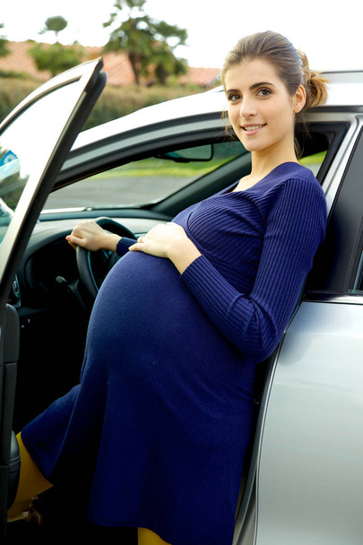 Happy smiling pregnant woman in front of car - 写真・画像