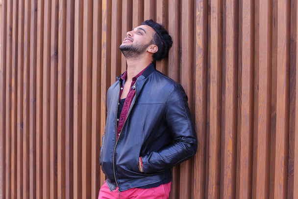 Mooie Arabische jongeman staat in de buurt van de muur en glimlacht, Laug - Foto, afbeelding