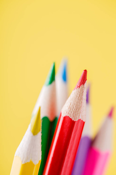 Close up of color pencils with different color over yellow background - Φωτογραφία, εικόνα